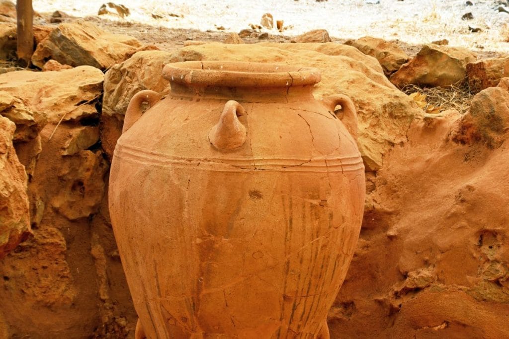 Large clay storage jar among stone remains in a Minoan archaeology site