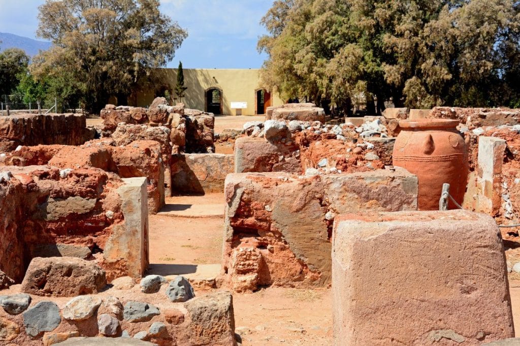 Clay storage jar and reddish stone walls at a Minoan archaeology site in Crete